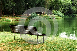 Outdoor wood chair in garden with pond, empty bench in park