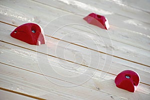 Outdoor wood climbing wall with three red holds. Home build training place.