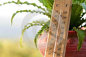 Outdoor wood thermometer calibrated in celsius and fahrenheit scale showing 15 degrees celsius or 60 degrees fahrenheit on terrace