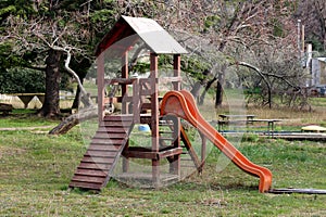 Outdoor wooden public playground equipment with climbing steps and slide