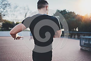 Outdoor Workout lifestyle concept.Young man stretching his body muscles before training.Muscular athlete wearing black