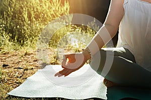 Outdoor yoga and meditation. Close-up of woman sitting on the beach on yoga mat in lotus position.