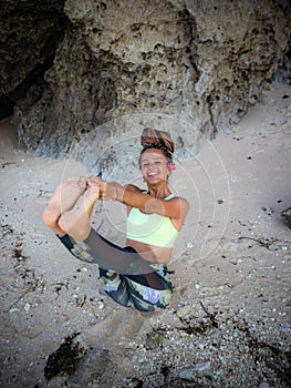 Outdoor yoga practice. Attractive woman practicing Ubhaya Padangusthasana, Wide-Angle Seated Forward Bend. Strengthen legs and photo