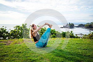 Outdoor yoga practice. Attractive woman practicing Ubhaya Padangusthasana, Wide-Angle Seated Forward Bend. Strengthen legs and photo