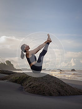 Outdoor yoga practice. Slim Asian woman practicing Ubhaya Padangusthasana, Wide-Angle Seated Forward Bend. Strengthen legs and photo
