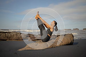 Outdoor yoga practice. Slim Asian woman practicing Ubhaya Padangusthasana, Wide-Angle Seated Forward Bend. Strengthen legs and