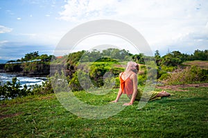 Outdoor yoga practice. Young woman practicing Bhujangasana, Cobra pose. Reclining back bending asana in hatha yoga. Tanah Lot