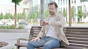 Outdoor Young Man Checking Time while Waiting on Bench