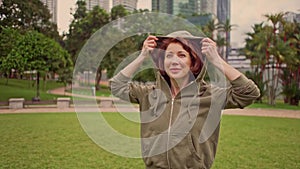 Outdoors 360 degree gimbal shot on young attractive and fit woman putting on hoodie starting running at green city park