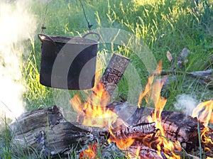 Outdoors on the bonfire of firewood cooked in a pot food for tourists