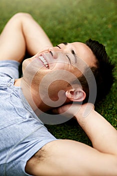 The outdoors bring a refreshing sense of calm. Shot of a handsome young man relaxing on the grass outdoors.