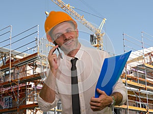 Corporate portrait of young attractive and successful engineer man or architect working on building at construction site wearing