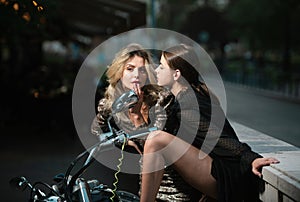 Outdoors fashion portrait of two modern women in city. High Fashion model woman posing in city street.