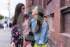 Outdoors fashion portrait young pretty best girls friends in friendly hug. Walking at the city. photo