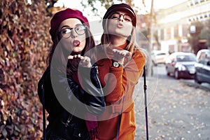 Outdoors fashion portrait young pretty best girls friends in friendly hug. Walking at the city. Posing at the street