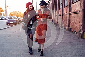 Outdoors fashion portrait young pretty best girls friends in friendly hug. Walking at the city. Posing at the street