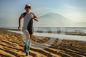 Outdoors fitness lifestyle portrait of young attractive and athletic woman in compression running socks jogging on the beach doing