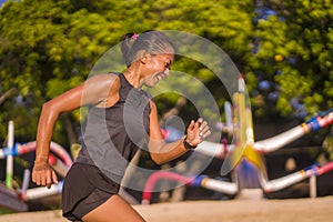 Outdoors fitness portrait of young attractive and athletic Asian Indonesian woman in her 40s running happy training at city park