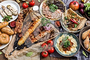 Outdoors Food Concept. Appetizing barbecued steak, sausages and grilled vegetables on a wooden picnic table.