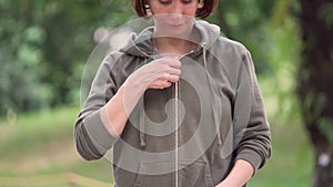 Outdoors gimbal shot on young attractive and fit woman zipping up hoodie starting running at green city park in morning jogging