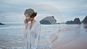 Outdoors girl talking mobile at rocky beach. Closeup smiling lady looking camera