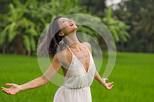 Outdoors holidays portrait of attractive and happy middle aged Asian Chinese woman in white dress enjoying freedom and nature at