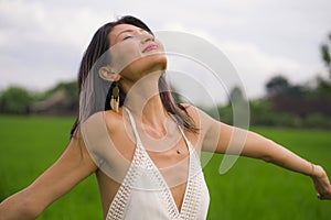 Outdoors holidays portrait of attractive and happy middle aged Asian Chinese woman in white dress enjoying freedom and nature at