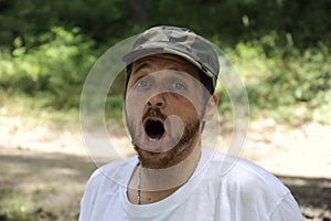 Outdoors horizontal portrait of happy hiker young man with red beard, feel good after hiking in forest. Traveler bearded male