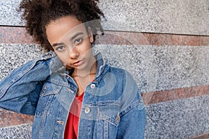 Outdoors Leisure. Young stylish african girl in denim jacket standing isolated on wall touching face smiling cute close