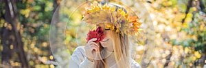 Outdoors lifestyle close up portrait of charming blonde young woman wearing a wreath of autumn leaves. Smiling, walking