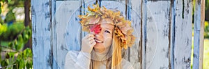 Outdoors lifestyle close up portrait of charming blonde young woman wearing a wreath of autumn leaves. Wearing stylish