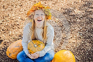 Outdoors lifestyle fashion image of happy beautiful girl sitting in autumn park. Holding a pumpkin. Wearing stylish