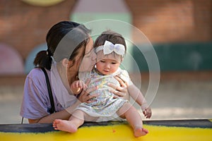 outdoors lifestyle portrait of Asian Chinese woman playing with beautiful and adorable baby girl smiling cheerful on playground