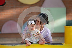 outdoors lifestyle portrait of Asian Chinese woman playing with beautiful and adorable baby girl smiling cheerful on playground