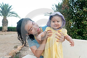 outdoors lifestyle portrait of Asian mother and her little daughter - beautiful woman holding his adorable and happy baby girl at