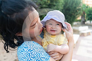 outdoors lifestyle portrait of Asian mother and her little daughter - beautiful woman holding his adorable and happy baby girl at