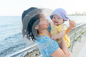 outdoors lifestyle portrait of Asian mother and her little daughter - beautiful woman holding his adorable and happy baby girl at