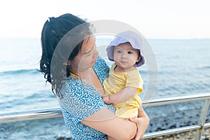 outdoors lifestyle portrait of Asian mother and her little daughter - beautiful woman holding his adorable and happy baby girl at