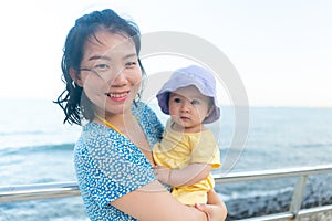 outdoors lifestyle portrait of Asian mother and her little daughter - beautiful woman holding his adorable and happy baby girl at