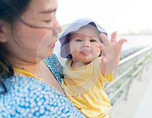 outdoors lifestyle portrait of Asian mother and her little daughter - beautiful woman holding his adorable and happy baby girl at