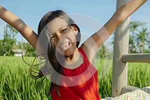 Outdoors lifestyle portrait of beautiful and sweet young girl smiling happy and cheerful, the excited child dressed in a cute red