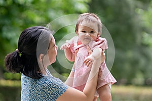 outdoors lifestyle portrait of mother and daughter - young happy and sweet Asian Korean woman playing with her 8 months baby girl