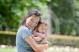 outdoors lifestyle portrait of mother and daughter - young happy and sweet Asian Korean woman playing with her 8 months baby girl