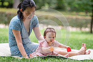 outdoors lifestyle portrait of mother and daughter - young happy and sweet Asian Korean woman playing with her 8 months baby girl