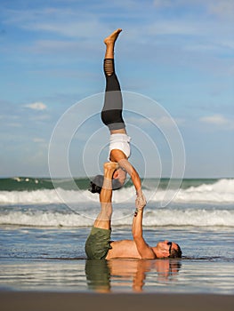 Outdoors lifestyle portrait young attractive and concentrated couple of yoga acrobats practicing acroyoga balance and meditation