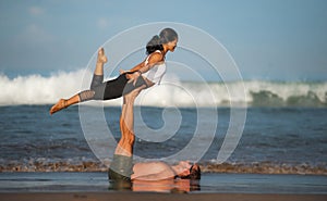 Outdoors lifestyle portrait young attractive and concentrated couple of yoga acrobats practicing acroyoga balance and meditation