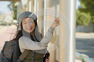 Outdoors lifestyle portrait of young beautiful and happy Asian Japanese woman waiting the train on station platform bench checking