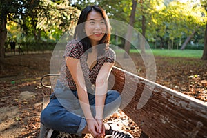 Outdoors lifestyle portrait of young happy and beautiful Asian Chinese woman enjoying relaxed and cheerful at sitting on city park