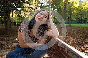 Outdoors lifestyle portrait of young happy and beautiful Asian Korean woman enjoying relaxed and cheerful at sitting on city park