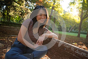 Outdoors lifestyle portrait of young happy and beautiful Asian Korean woman enjoying relaxed and cheerful at sitting on city park